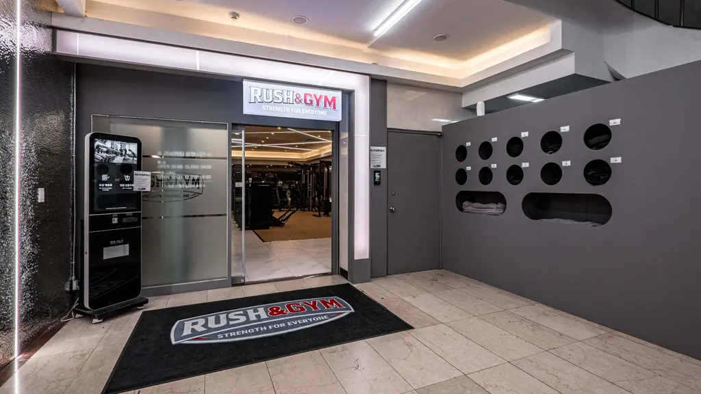 양재 러쉬앤짐 입구 완공 사진: RUSH&GYM 사인과 유리문, 원형 타공 벽
