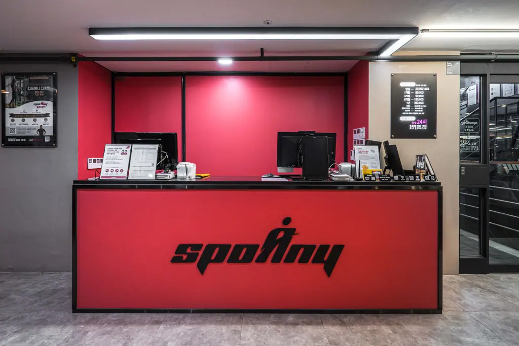 스포애니 교대역점 리셉션: 붉은 벽면과 spoAny 로고 데스크